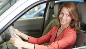 Red-headed young woman sitting in a new car