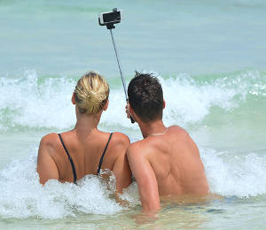 Young man and woman in ocean taking a selfie
